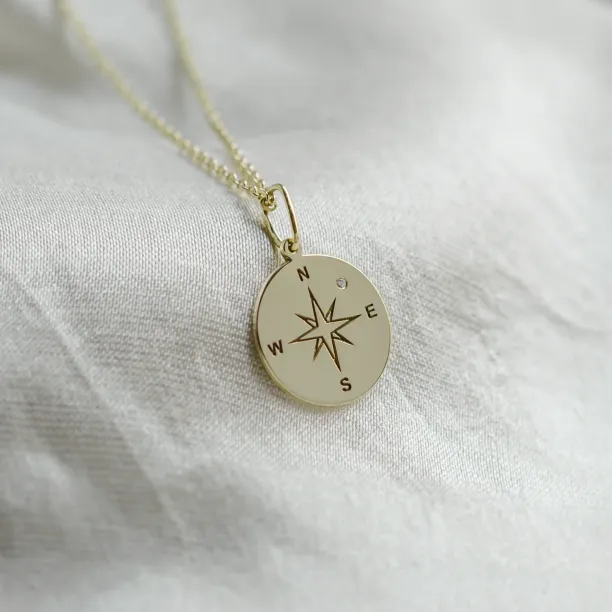 Gold pendant with a compass and a diamond MAP Image